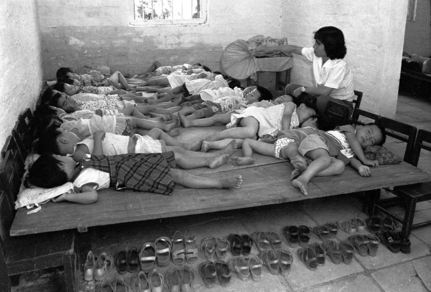 父母心：赤沙幼儿园的孩子们正在午休，教师为他们驱蚊纳凉。（广州赤沙村 1978）.png